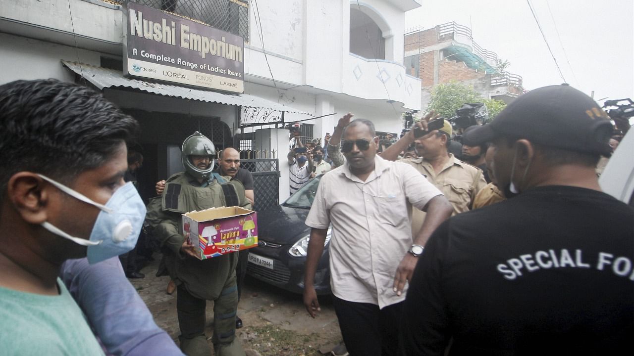 Uttar Pradesh ATS personnel carry a pressure cooker bomb and other heavy explosives recovered after arresting two accused allegedly linked with Al Qaeda module, in Dubagga area of Lucknow, Sunday. July 11, 2021. Credit: PTI Photo