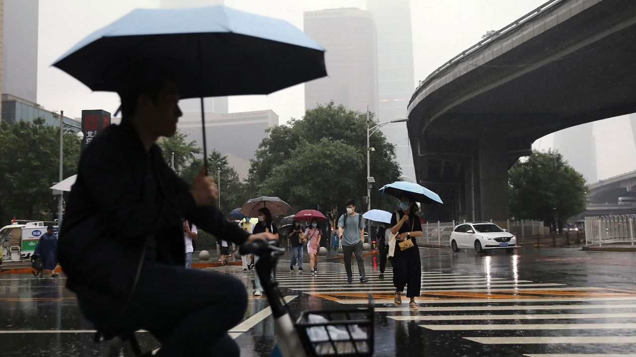People are seen amid heavy rainfall during morning rush hour in Beijing’s Central Business District (CBD). Credit: Reuters photo