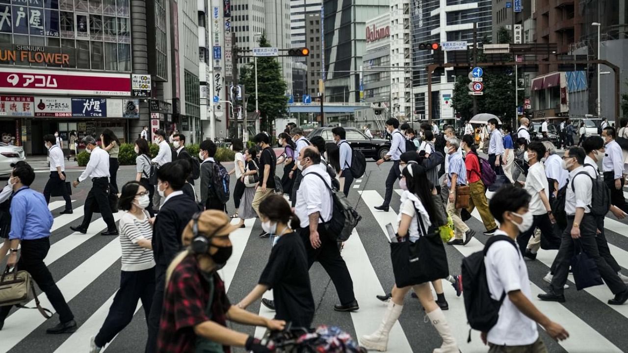 Commuters cross the street during a morning rush hour ahead of the 2020 Summer Olympics, Tuesday, July 13, 2021, in Tokyo. Credit: AP Photo