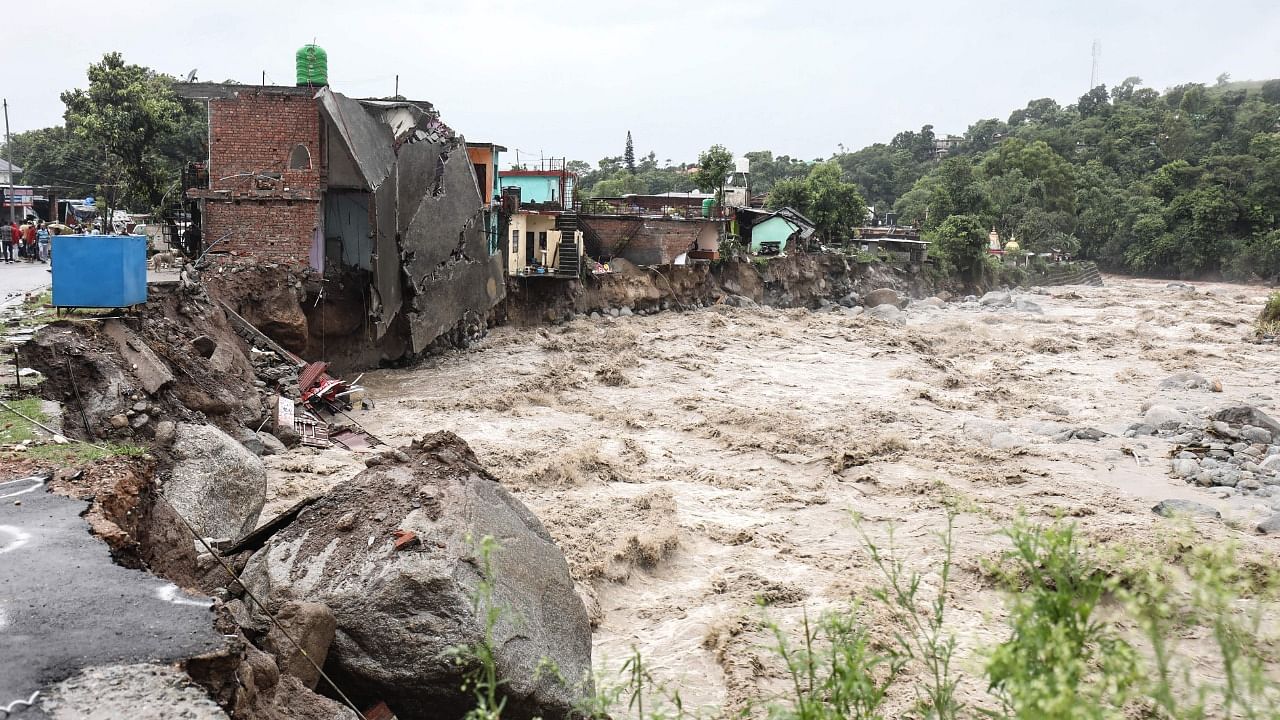 Damaged houses along the banks of the overflowing Manjhi River are pictured following heavy rains in Bagli village, from Dharamshala. Credit: AFP Photo