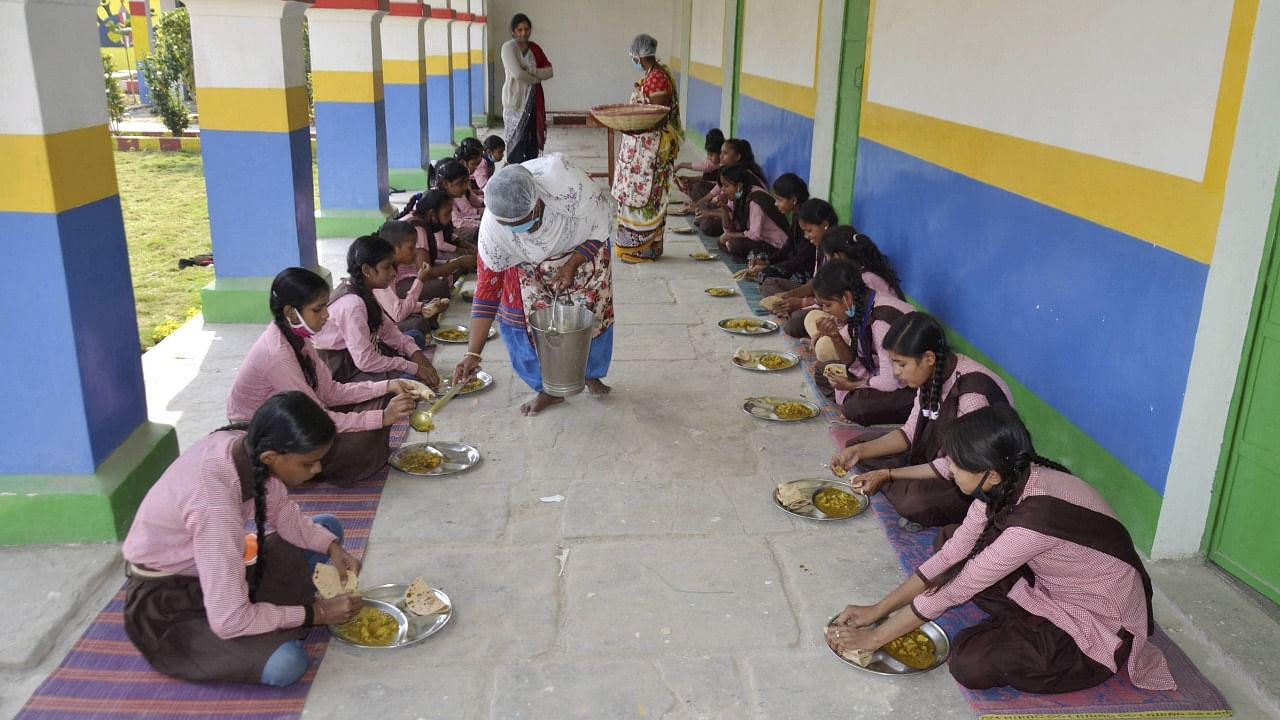 Students have mid-day meal at a government school, after it re-opened for 6th to 8th standard students since it closure in March owing to the coronavirus pandemic, in Mirzapur. Credit: PTI photo