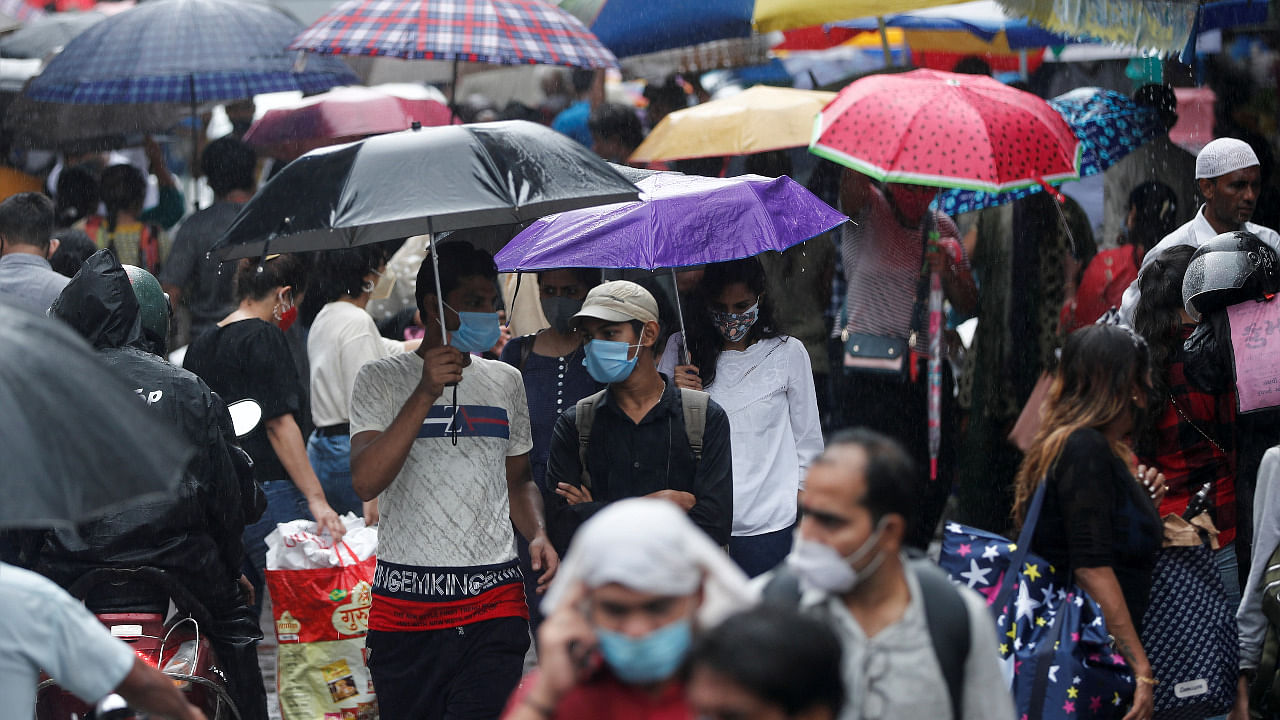 People walk through a crowded market on a rainy day amidst the spread of Covid-19 in Mumbai. Credit: Reuters Photo