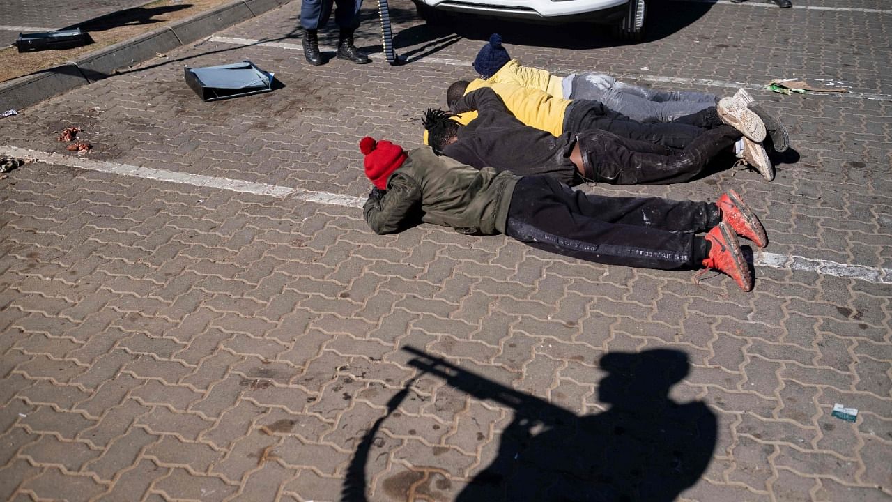 Suspected looters lie on the ground as they are being detained by South African Police Service (SAPS) officers in a mall near Johannesburg. Credit: AFP Photo