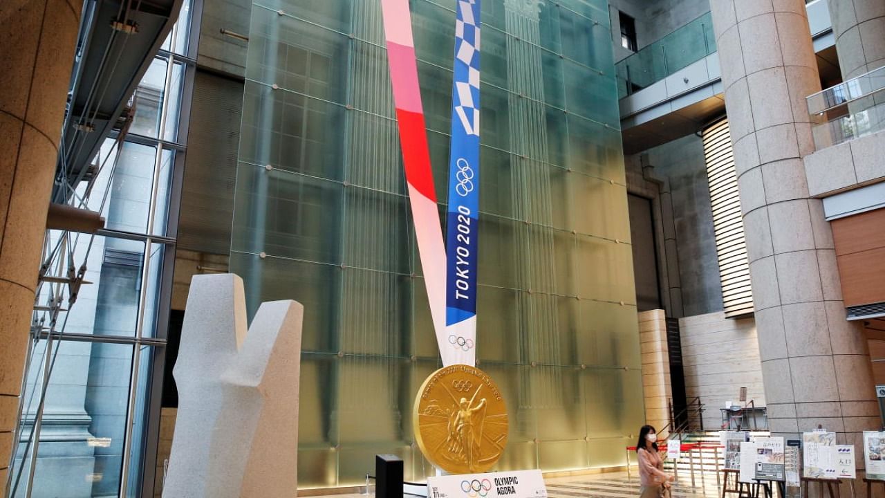 A woman walks past a large-scale reproduction of Tokyo 2020 Olympic Games medal at Nihonbashi Mitsui Tower in Tokyo. Credit: Reuters Photo