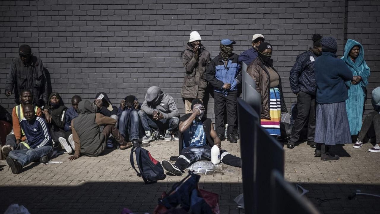 A man detained for looting washes his face with milk as he sits with others while in police custody at a mall in Vosloorus. Credit: AFP Photo
