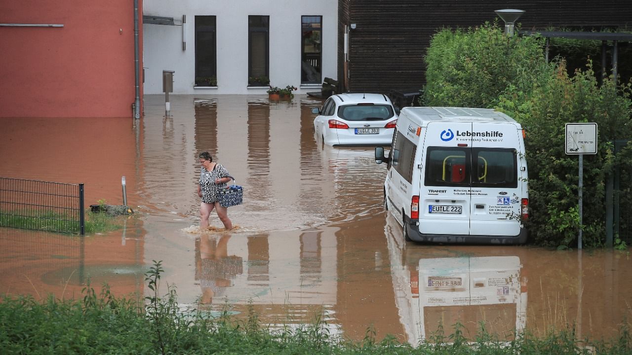 A woman wades across floodwater as she goes out shopping following heavy rainfalls in Gross-Vernich. Credit: Reuters Photo