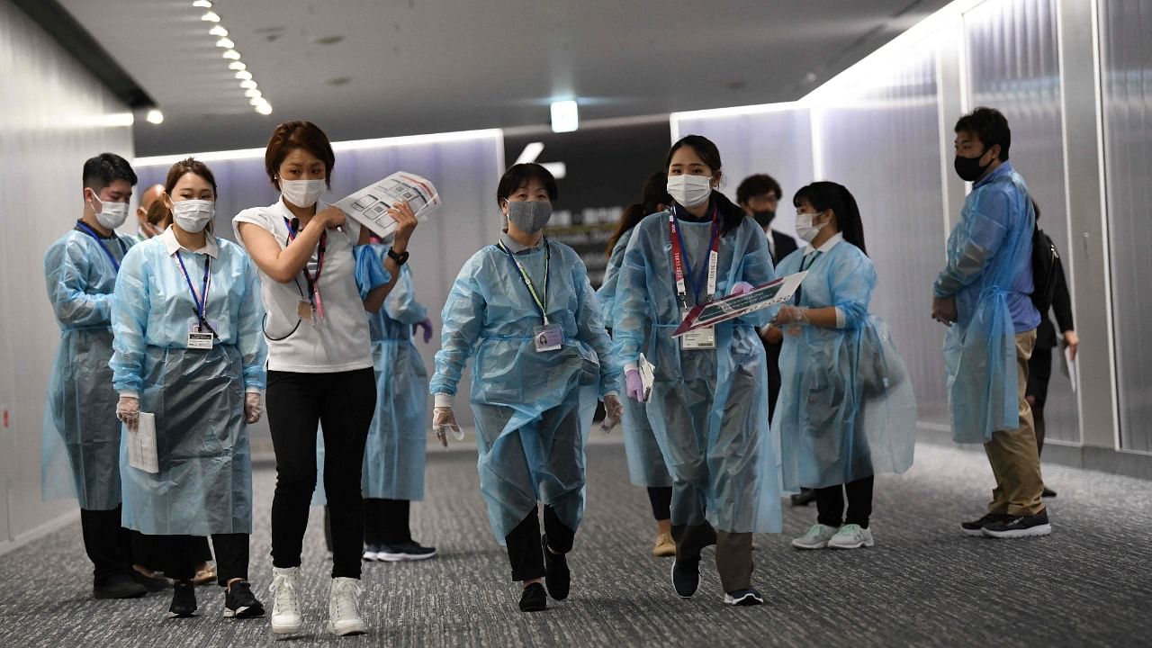 Airport operations crew for the Tokyo 2020 gather at an arrival gate to guide the Olympic delegation at Narita international airport in Narita, Chiba prefecture on July 14, 2021. Credit: AFP Photo