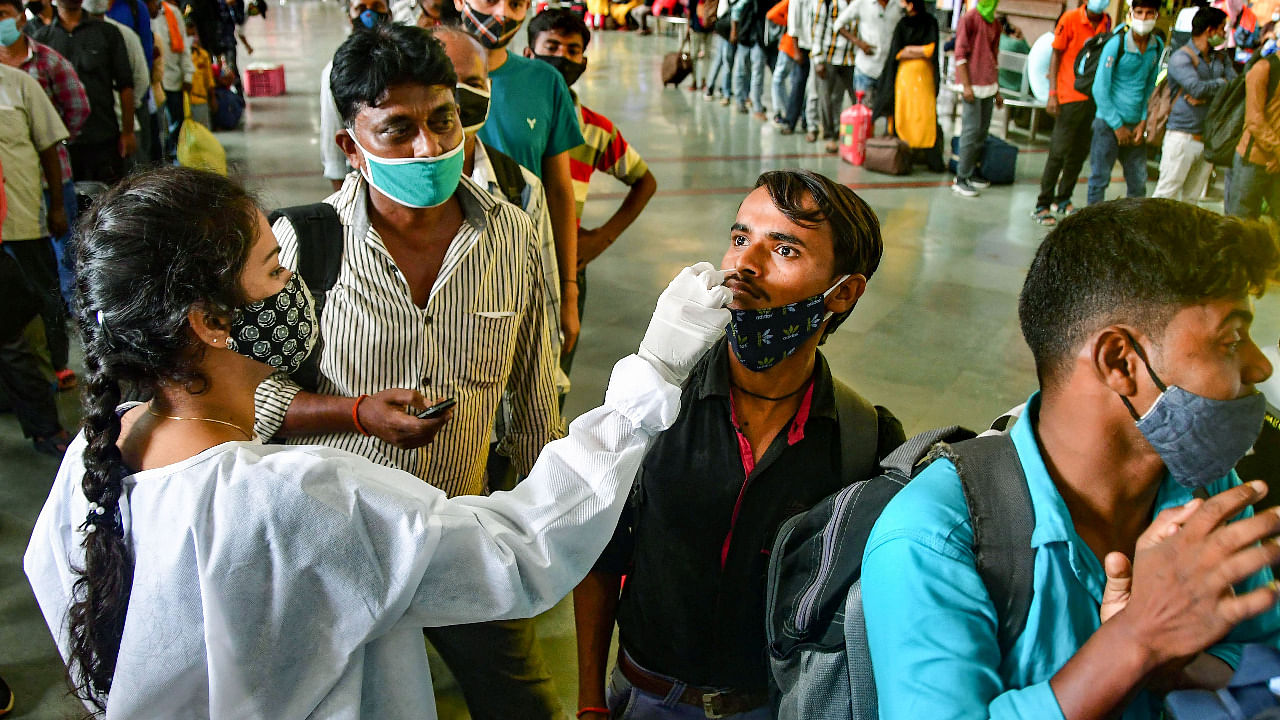 A BMC health worker collects swab sample of a passenger for Covid-19 test, at the CSMT station, in Mumbai. Credit: PTI Photo