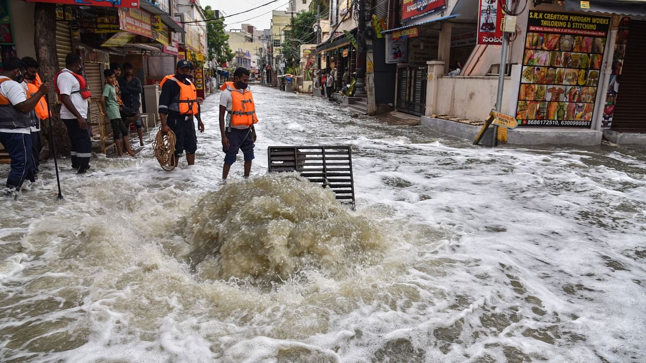 DRF team tries to clean the overflowing drain due to heavy rains from past two days, in Hyderabad. Credit: PTI Photo