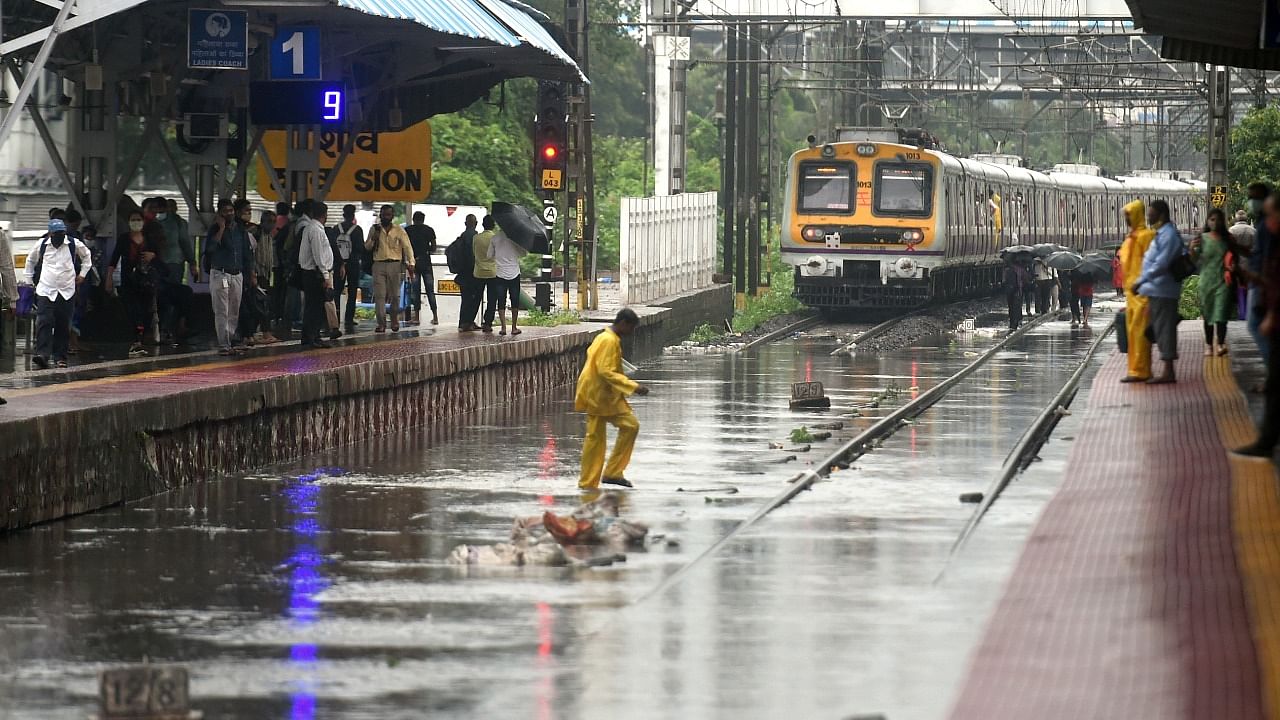 People wait at Sion Station after local train services were affected due to waterlogging after heavy rains, in Mumbai. Credit: PTI photo