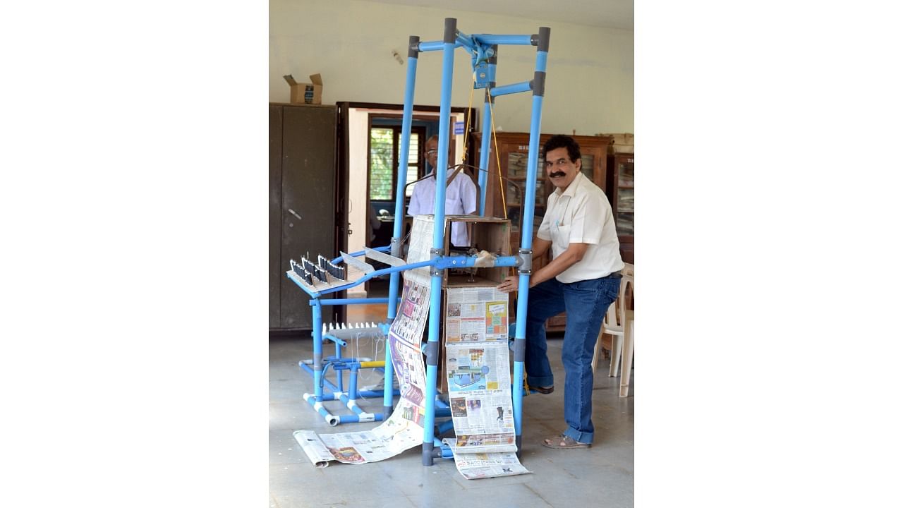 Dhananjay Hegde with the demo machine developed by him to prepare an improvised paper bag. DH File Photo