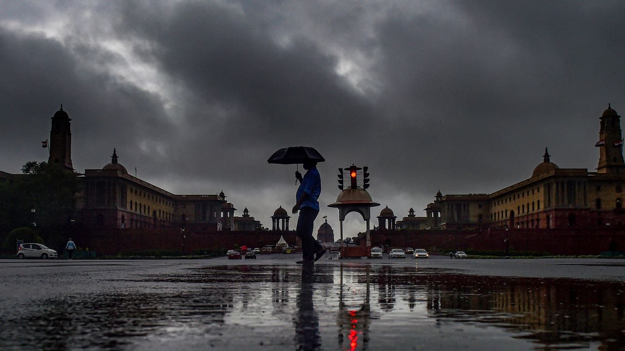 A man who carries an umbrella walk past Vijay Chowk during rains in New Delhi, Wednesday, July 14, 2021. Credit: PTI Photo