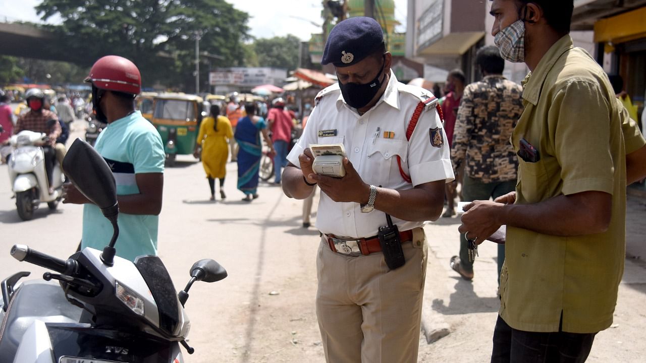 A traffic police officer collects fine from people who violated traffic rule. Credit: DH Photo/S K Dinesh