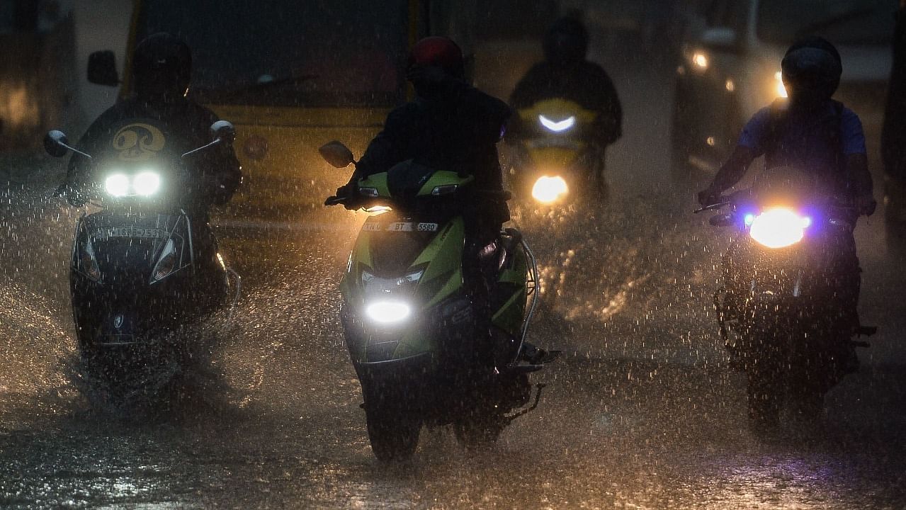 Commuters make their way along the road as it rains in Chennai. Credit: AFP Photo