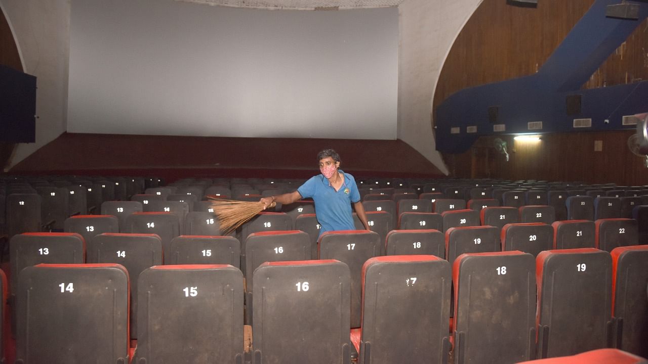 A worker cleans a theatre ahead of its reopening in Bengaluru on Sunday. Credit: DH Photo/ S K Dinesh