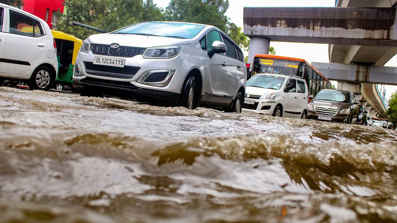 Commuters wade through a waterlogged road after heavy rain at Model Town area in New Delhi, Wednesday, July 14, 2021. Credit: PTI Photo