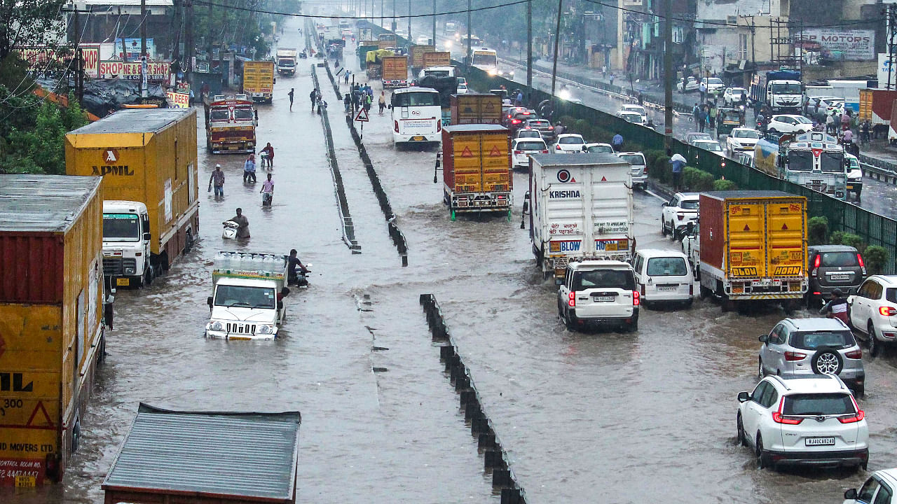 Commuters wade through waterlogged Delhi- Gurugram Expressway and service road after heavy rains. Credit: PTI Photo
