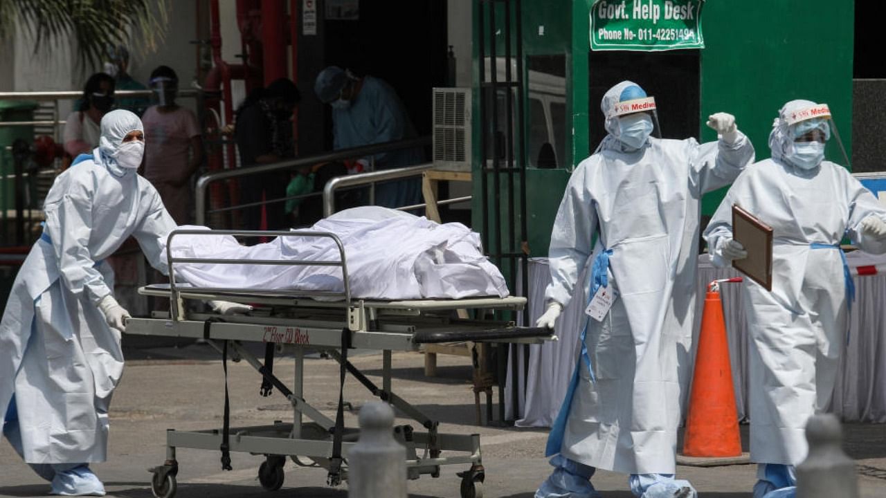Health workers wearing protective suits carry the body of a Covid-19 victim at Sir Ganga Ram Hospital in New Delhi. Credit: PTI Photo