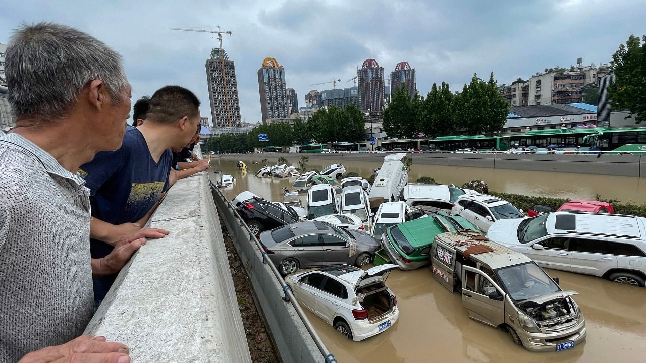 People look out at cars sitting in floodwaters. Credit: AFP Photo