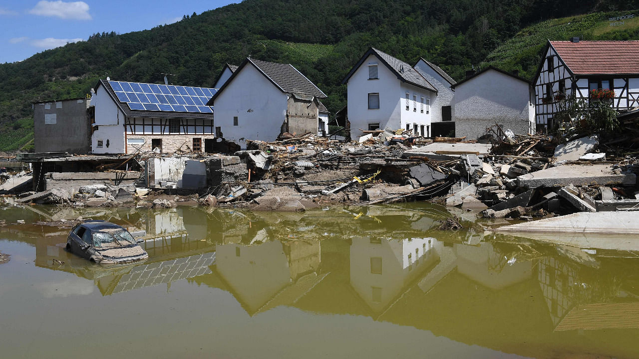 Damaged houses reflect onto the surface of the still brown water as a mount of debris and a damaged car lie in it in Rech, Rhineland-Palatinate, western Germany. Credit: AFP Photo