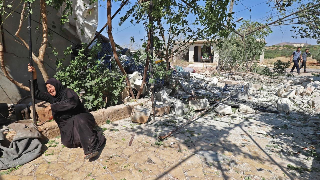 A Syrian woman reacts near the ruins of a house, destroyed in a reported regime artillery shelling, in the village of Iblin in Syria's rebel-held northwestern Idlib province. Credit: AFP Photo
