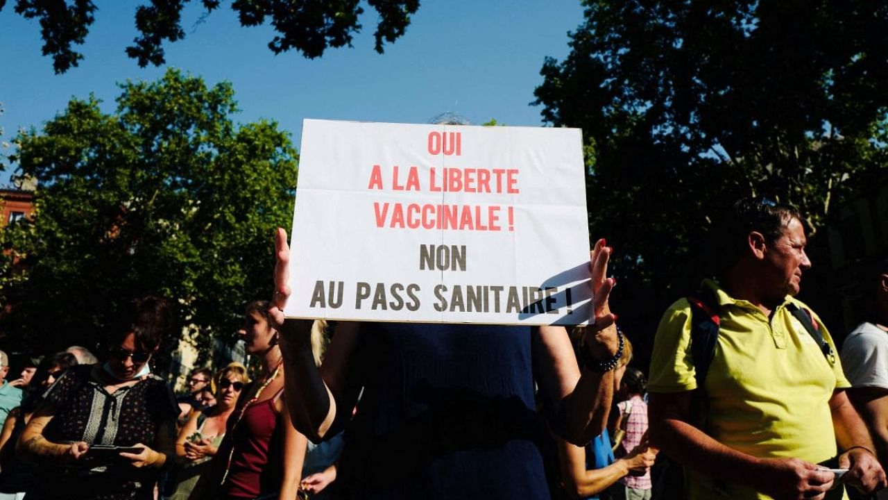 A protester holds a banner which reads : "Yes for vaccinal freedom, no for health passport!" as she demonstrates against the health pass, in Toulouse, south western France. Credit: AFP Photo