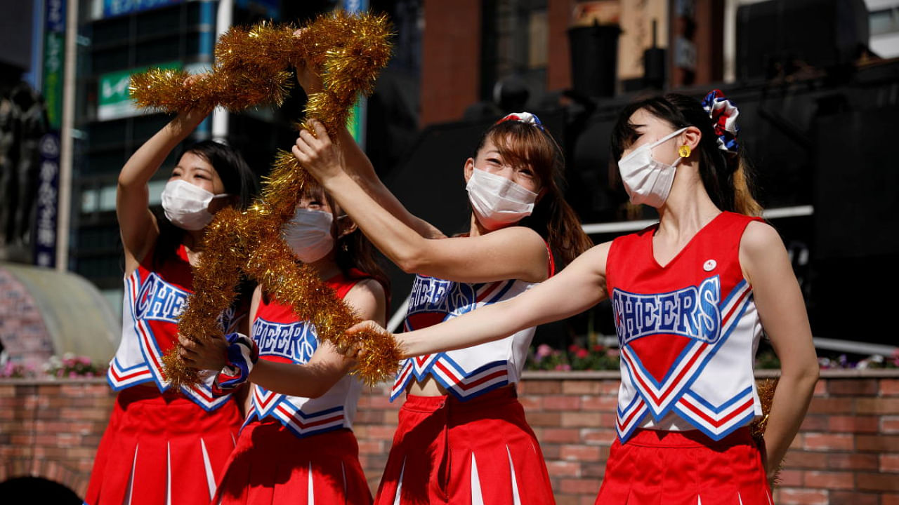 Cheerleaders from the "All Japan Cheer Organization" perform in protective masks due to COVID-19, to cheer people up in front of Shimbashi Station, one day before the start of the Tokyo 2020 Olympics in Tokyo. Credit: Reuters Photo