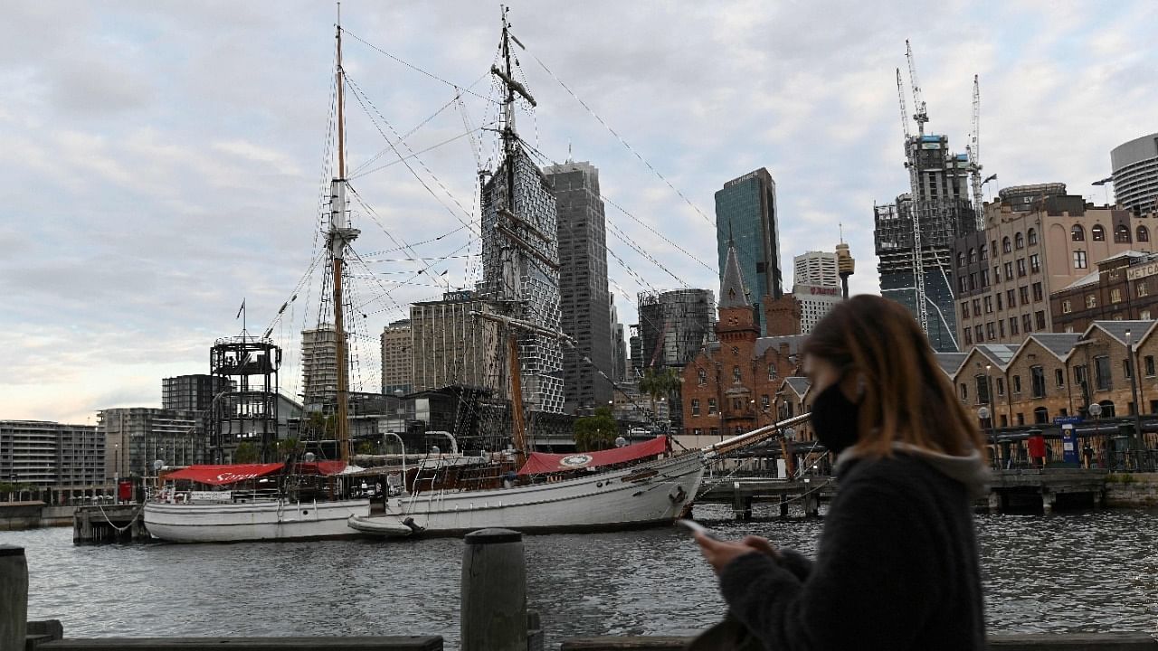 A woman wearing a face mask walks along the quiet Sydney Harbour amid the lockdown. Credit: AFP photo