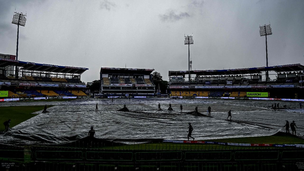 Ground staff personnel cover the ground as rain stops play during the third ODI between Sri Lanka and India at the R.Premadasa Stadium in Colombo. Credit: AFP Photo