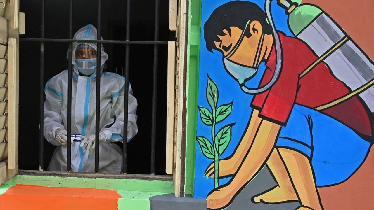 A health worker wearing a protective suit stands behind a window of a newly-inaugurated 'Oxygen Hub' for Covid-19 patients in Kolkata on May 23, 2021. Credit: AFP Photo
