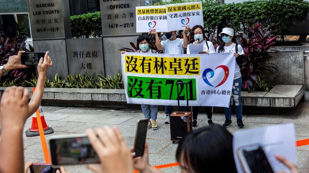 Supporters (C) of the defendants hold placards outside the Wanchai district court in Hong Kong on July 22, 2021, as seven men face sentencing for different counts of rioting and wounding for attacking pro-democracy protesters in the city's Yuen Long area in 2019. Credit: AFP Photo