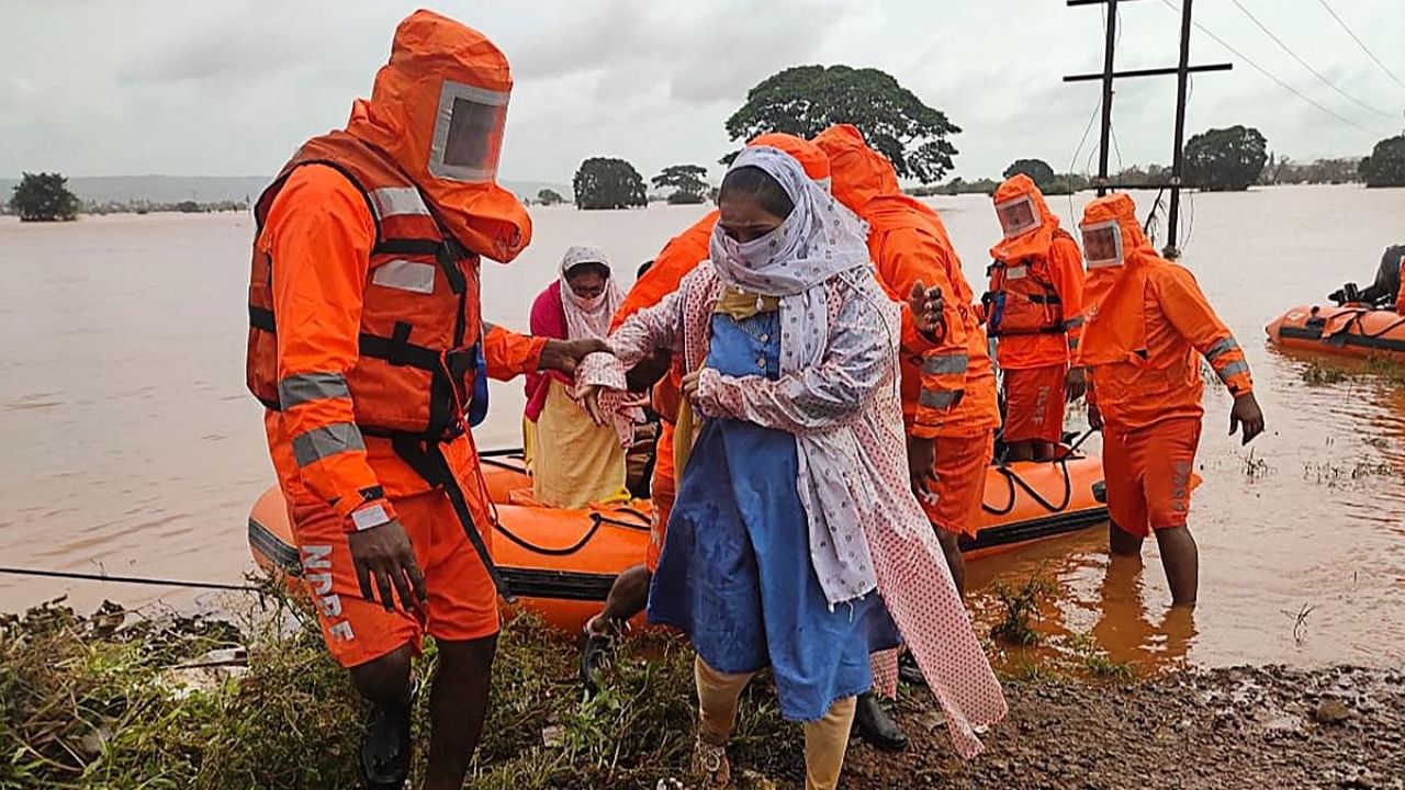 This handout photo taken on July 25, 2021 and released by the India's National Disaster Response Force (NDRF), shows NDRF personnel rescuing stranded villagers from flooded areas following heavy monsoon rains in Balinge village of Kolhapur district of Maharashtra. Credit: NDRF/AFP Photo