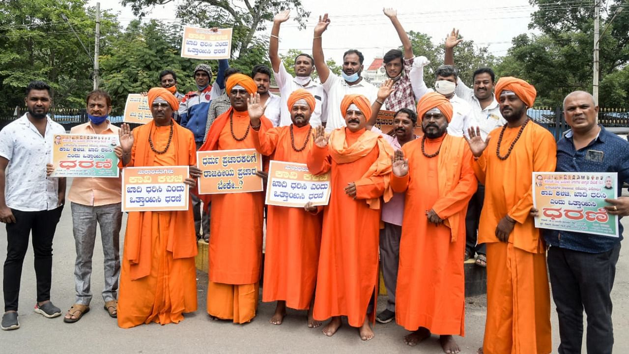 The members of Karnataka State Backward Classes Awareness Forum dressed up as seers stage a protest near district court complex in Mysuru on Sunday. Credit: DH Photo