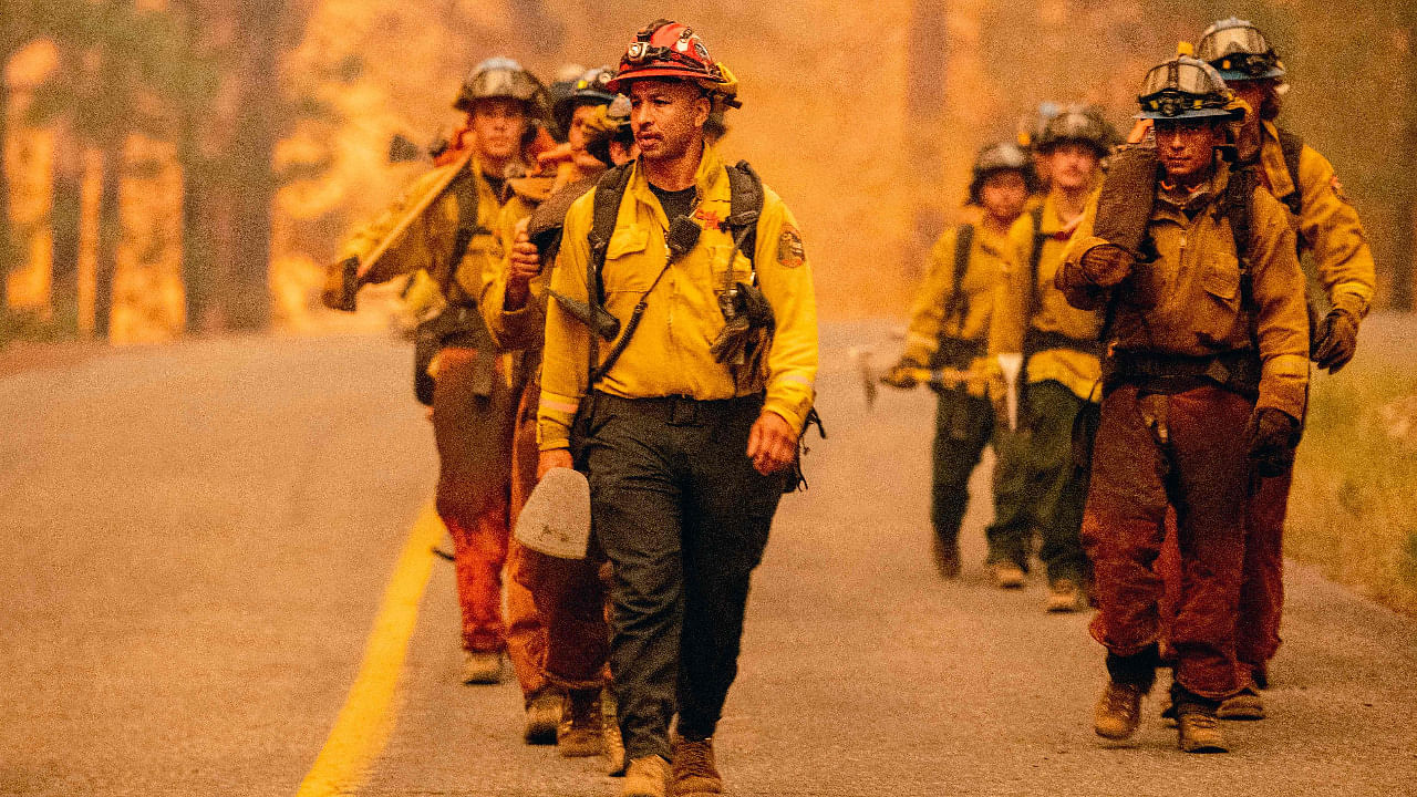 A crew of firefighters walk along a road while working the scene during the Dixie fire in the Prattville community of unincorporated Plumas County. Credit: AFP Photo