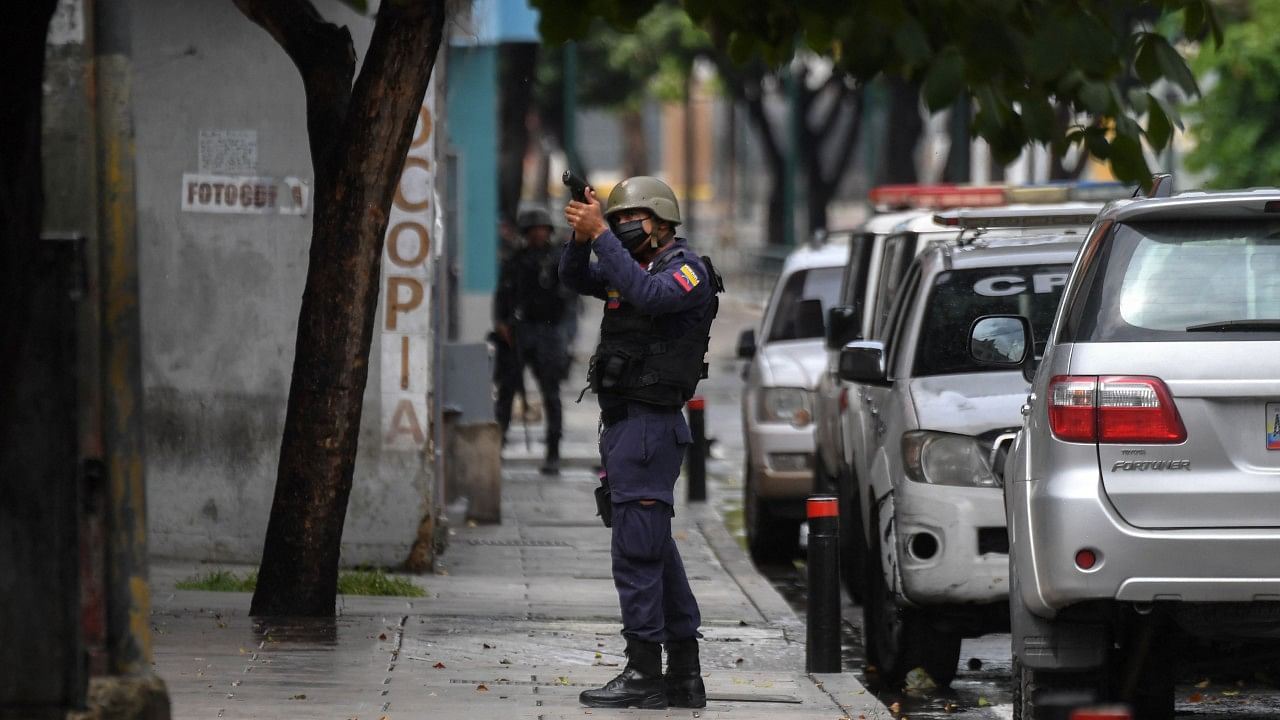 A member of the Bolivarian Police aims at a possible target after clashes with alleged members of a criminal gang at the Cota 905 neighborhood, in Caracas. Credit: AFP Photo