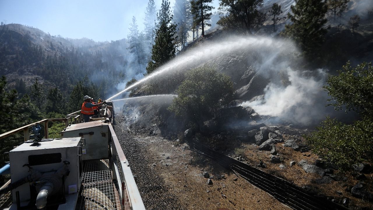 Firefighters assigned to the Union Pacific Fire Train protect the tracks and hinder the Dixie Fire from crossing the North Fork of the Feather River in Plumas National Forest. Credit: Reuters photo
