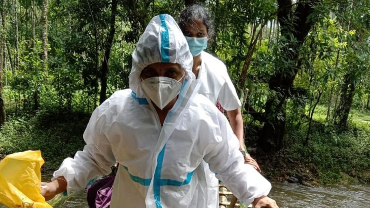 Wearing PPE kit, the staff of Kollamogru PHC crossing a delicate wooden bridge, to reach Idyadka in Kalmakar. Credit: DH Photo