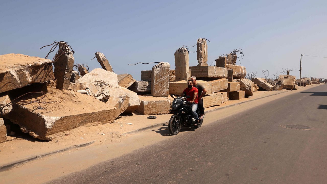 A Palestinian man rides a motorcycle past rubble from buildings destroyed during the latest violence between the Palestinian Hamas and Israel, in front of the al-Shatii refugee camp, in Gaza. Credit: AFP Photo