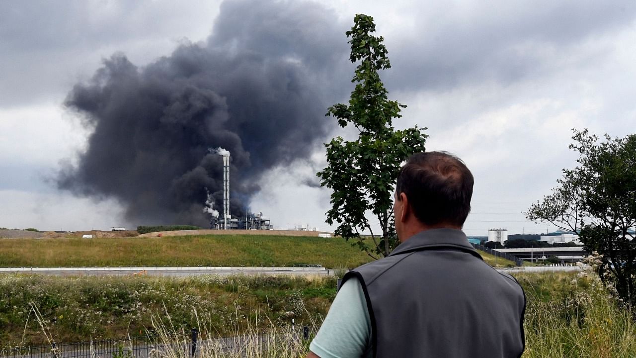 An onlooker watches as smoke rises from a landfill and waste incineration area at the Chempark industrial park run by operator Currenta following an explosion in Leverkusen's Buerrig district, western Germany, on July 27, 2021. Credit: AFP Photo