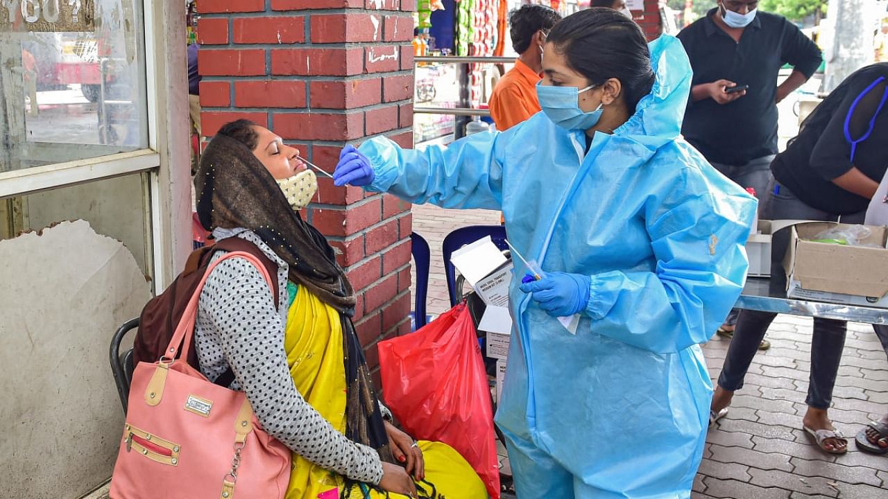 A health worker collects swab sample of a passenger for Covid-19 test, at Majestic bus stand in Bengaluru, Thursday, July 15, 2021. Credit: PTI Photo