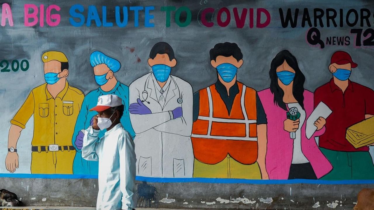 A man walks past an informative Covid-19 coronavirus mural painted on a wall along a road in Hyderabad on July 28, 2021. Credit: AFP Photo