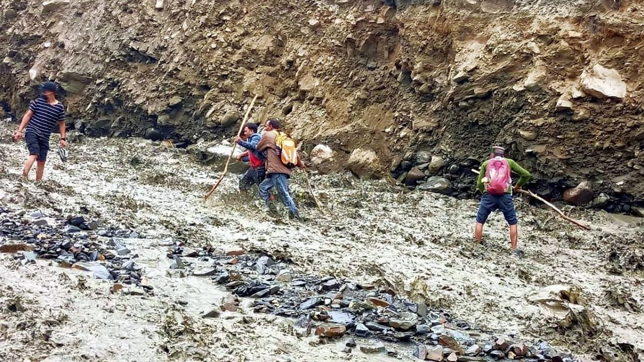People risk their lives while crossing the Jahmala Nala, a day after a bridge over this was washed away due to the cloudburst, in Lahaul Spiti district, Thursday, July 29, 2021. Credit: PTI Photo