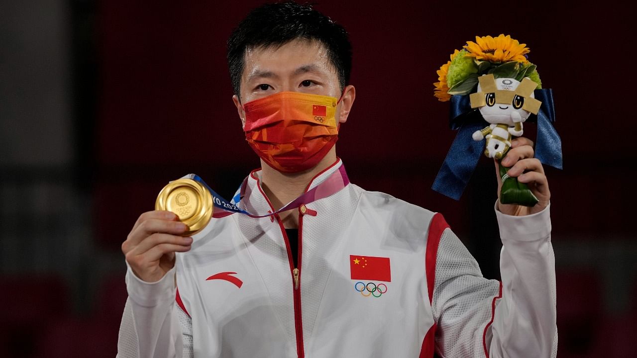 Ma Long of China celebrates with his gold medal for the table tennis men's singles at the 2020 Summer Olympics. Credit: AP Photo