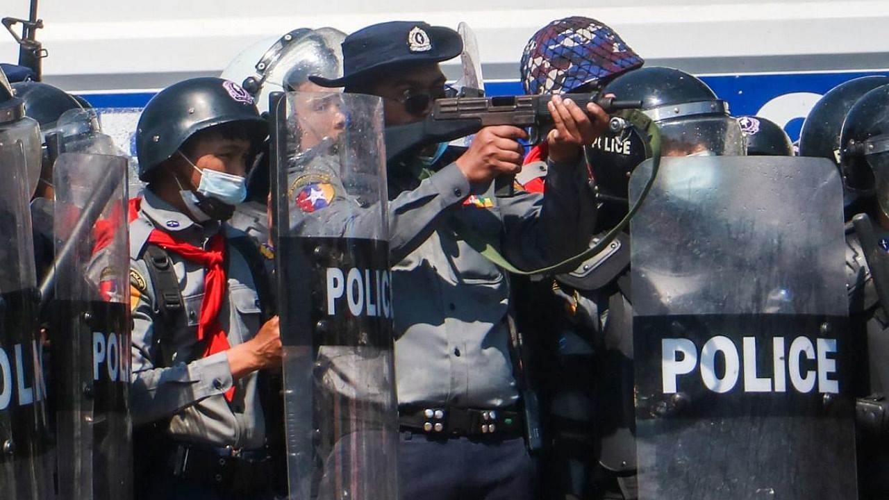 In this file photo taken on February 9, 2021, a police officer (C) aims a gun during clashes with protesters taking part in a demonstration against the military coup in Naypyidaw. Credit: AFP Photo