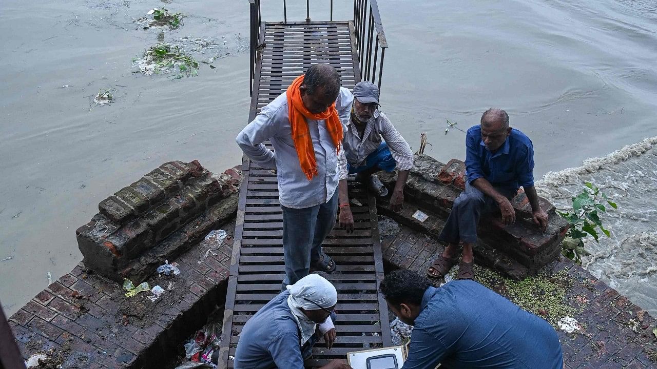 Indian railways employees check the raised water levels in Yamuna river after heavy rains in New Delhi. Credit: AFP Photo