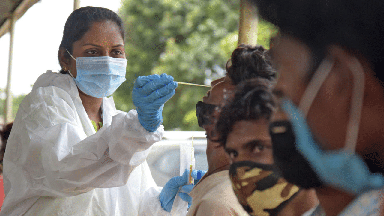 A healthcare worker collects swab samples for coronavirus from people at city railway station in Bengaluru. Credit: DH Photo/Pushkar V