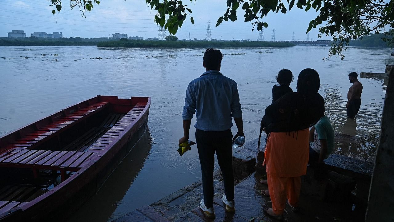 People watch as the water levels rises in the river Yamuna. Credit: AFP Photo