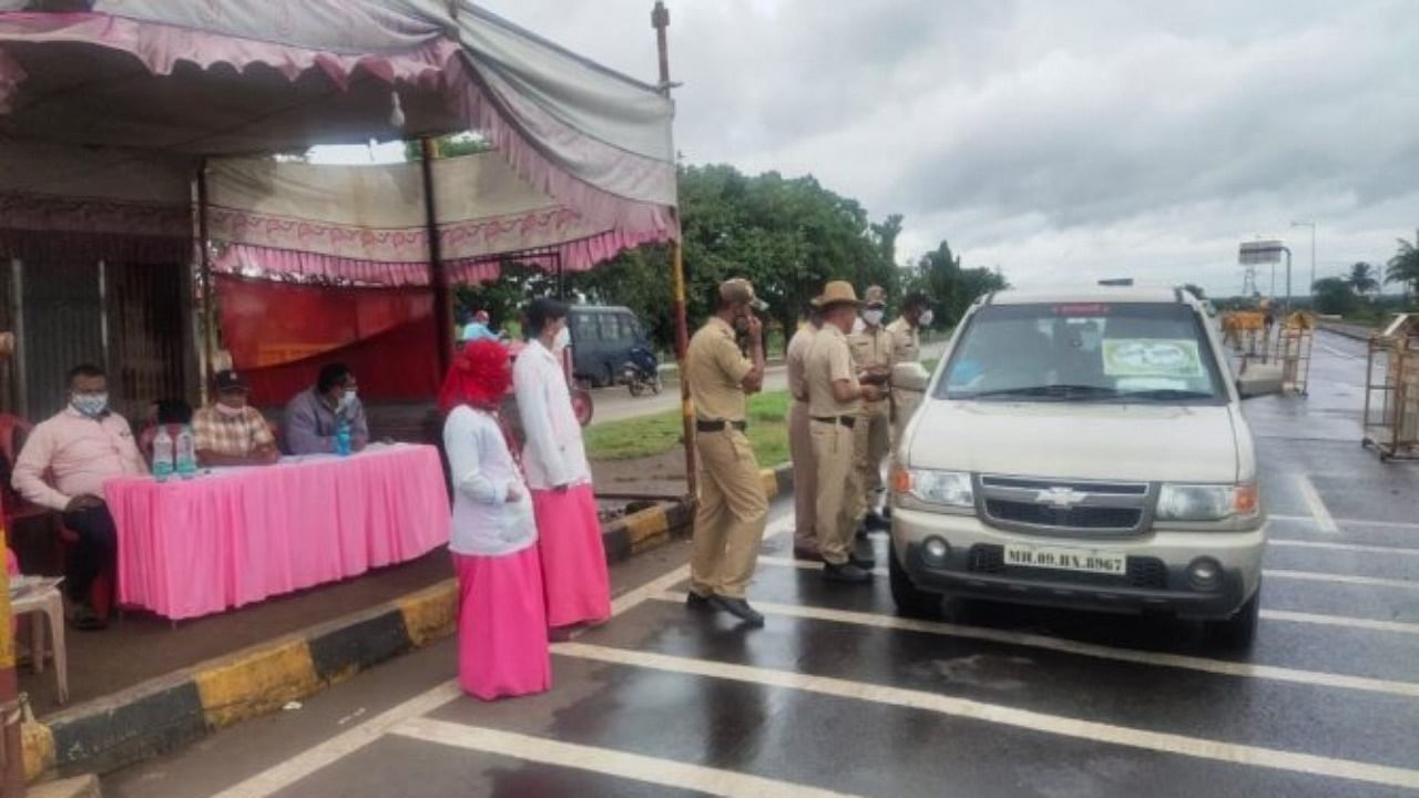 Police and Asha workers verifying Covid-19 vaccination and RT-PCR negative report at Kognoli check post in Nippani taluk in Belagavi district along the Pune-Bengaluru national highway. Credit: DH Photo