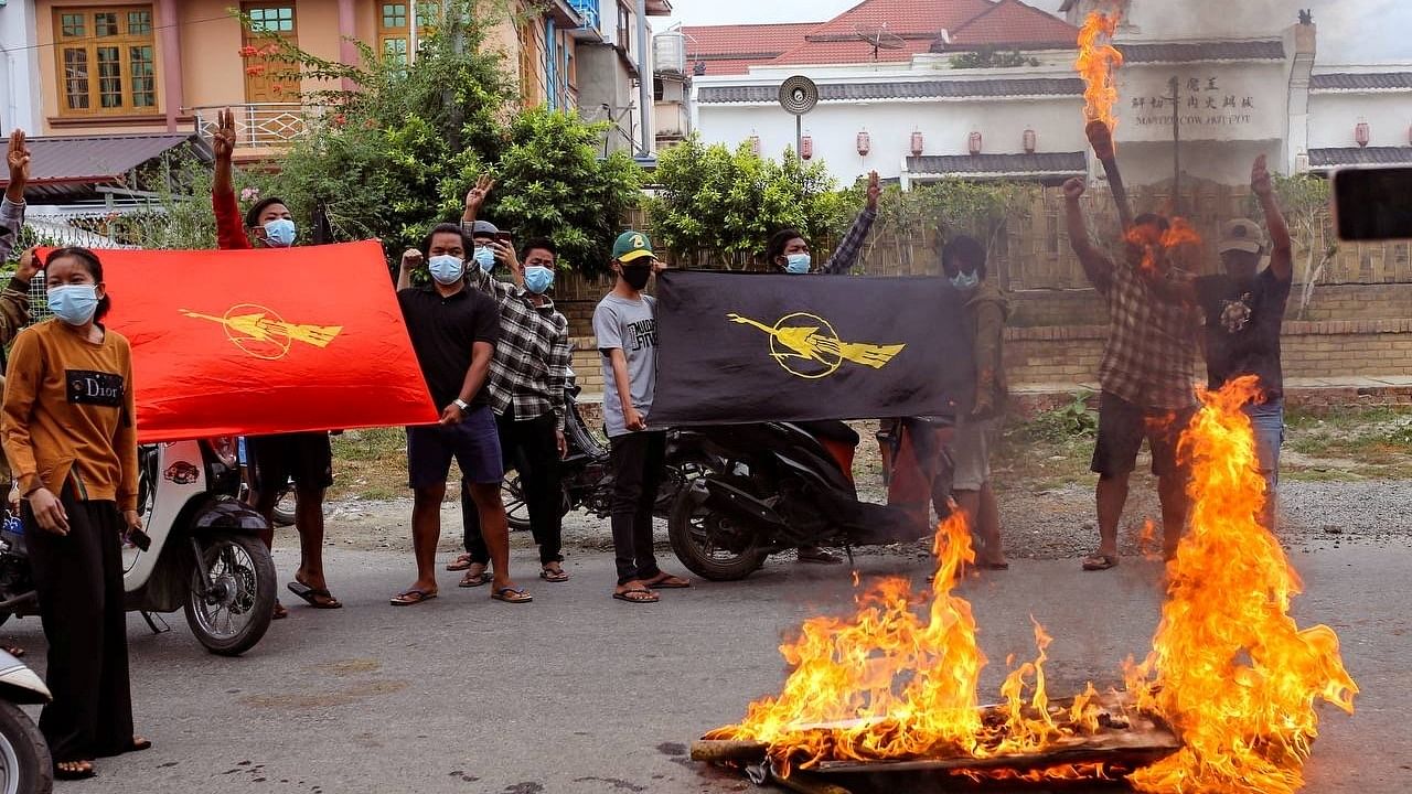 Demonstrators display flags and the three-finger salute as they torch a mock coffin with pictures of Myanmar's army ruler Min Aung Hlaing on his birthday in Mandalay, Myanmar July 3, 2021. Credit: Time For Revolution/Handout via Reuters