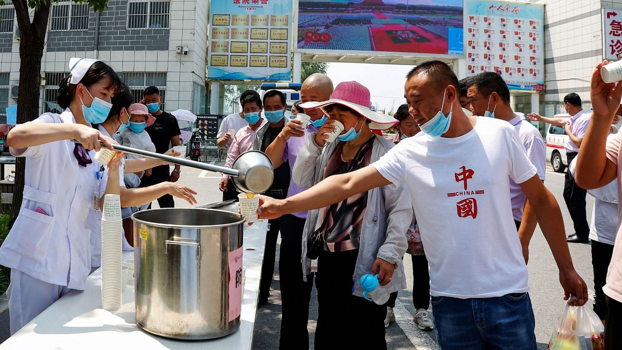 A staff member distributes free traditional Chinese medicine amid a rise in Covid-19 coronavirus cases across the country in Sihong, Suqian city, in China's eastern Jiangsu province on August 1, 2021. Credit: AFP Photo